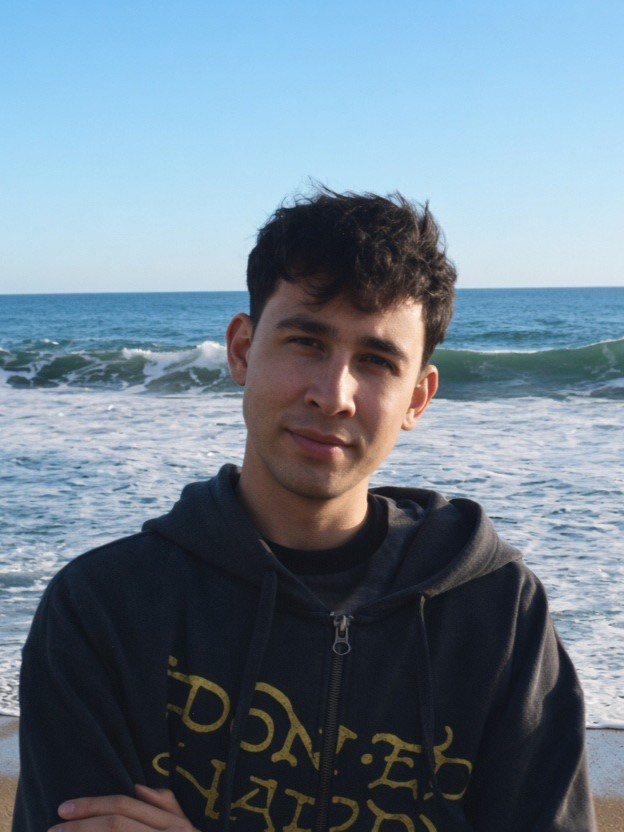 Artie Parada standing on a beach, waves breaking behind him